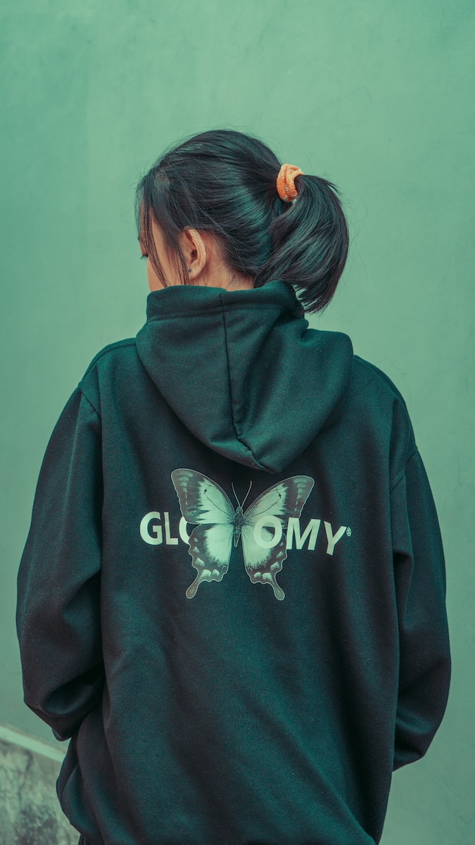 a woman wearing a green hoodie with a butterfly on it